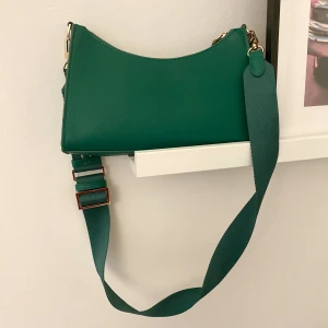 Axelremsväska grön med gulddetaljer - Bra skick! Långt axelband som är justerbart. 