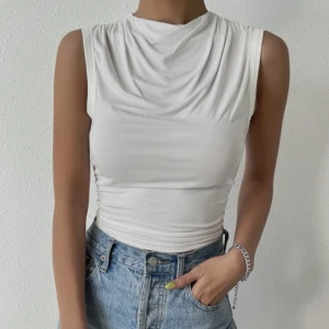 Topp - Vit topp som inte kommit till användning. En enkel Tshirt med fina detaljer upptill, utan ärmar.