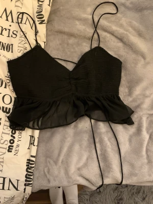 Topp svart med snöre  - Oandvänd topp som man knyter där bak. 