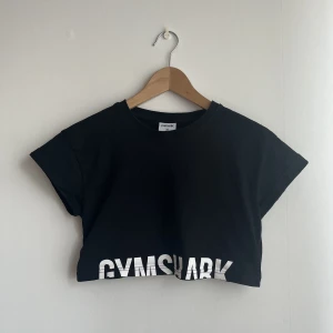 Croppad tröja från Gymshark - Svart kort crop top från Gymshark. Storlek XS. Finns ej längre tillgänglig i svart xs på hemsidan. Sparsamt använd och i fint skick! 