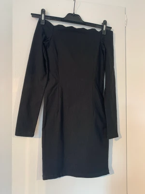 Svart offshoulder klänning - Svart tight offsoulder klänning från Oneness stl s Fint skick, finns en dold dragkedja på sidan.