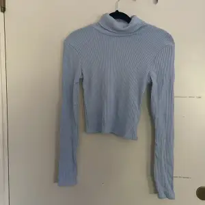 En skön ljusblå polo tröja som är ribbad.