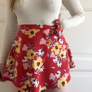  Omlott-minikjol  - Kort kjol med superhärligt färgglatt mönster. Omlott modell, knyts fast i midjan. HM Divided, str 34. Använd 1 gång. 