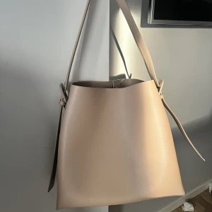 Väska mango - Jag säljer min väska från mango i modell ”shopperväska detalj spänne” i beige färg. Den är endast använd två gånger men var tyvärr lite för liten för att få plats med alla mina skolböcker. Väldigt fin och perfekt längd på band för att bära på axeln. 