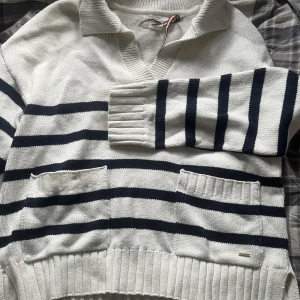 Randig stickad tröja  - Snygg och bekväm randig stickad tröja med fickor fram och slits på sidan. Helt oanvänd! 