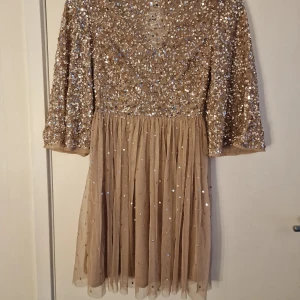 Glittrig klänning  - Fin champagne/guld färgad kort klänning, med glittriga paljetter. Använd en gång, så därfor i fint skick. Storlek 34. 🥳 