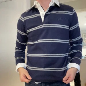 En snygg rugbytröja från GANT - En riktigt snygg gant rugbytröja i storlek Small.  Den är väldigt fin och man ser knappt att den har blivit använd! Perfekt att ha en skjorta / tshirt under!  Om du har några frågor eller vill ha fler bilder är det bara att höra av dig!  Mvh David