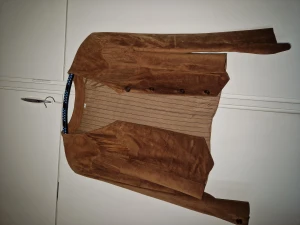 Moccajacka med fransar - Jacka i äkta mocca i fint skick. Lite kortare modell. Längd rygg: 58 cm. Ärmlängd 56 Storlek 42.