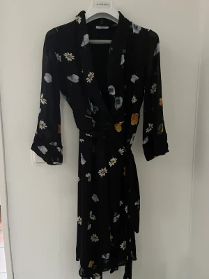 Ganni klänning  - Superfint Ganni klänning, svart med tryckta blommor och tunnare tyg på ärmarna.