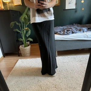 Långkjol - Svart långkjol i silkesmatrial. Knappt använd. Jag är 178 cm och går hela vägen till golvet på mig. 