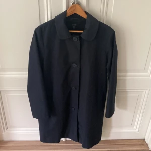 Marinblå rock COS - Marinblå trenchcoat med rundad krage från COS i 100% bomull. Produkten är knappt använd och i gott skick. Storlek 38. Nyligen kemtvättad. 