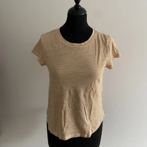 Randig T-shirt  - Enkel randig T-shirt från HM i Strl xs. Ränderna drar åt camelbrun i färg. 