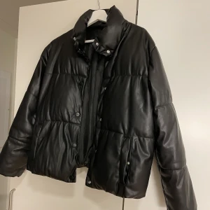 PUFFER JACKET - Puffig jacka i PU-läder (fake läder) med högre krage och knappar för att stänga. Köpt från Vero Moda för ett par år sen Använd sparsamt! Finns inga fel så ser ut som ny. Storlek M men skulle säga att den passar en som har S också. Jag brukar ha både S/M