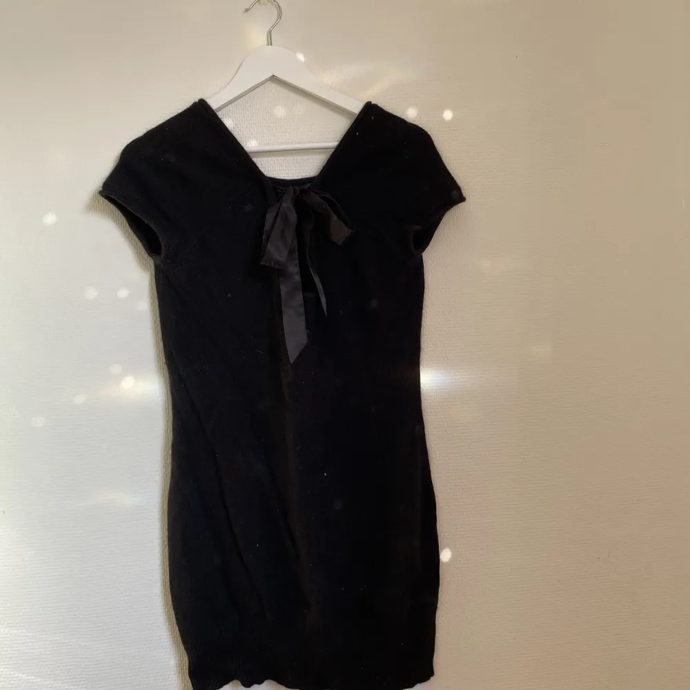 En superfin svart stickad klänning i bland annat angora och ull. Klänningen har en cutout detalj på baksidan där man knyter med en rosett. Klänningen har ett litet hål på ena axeln kan skicka bild om det efterfrågas.. Klänningar.