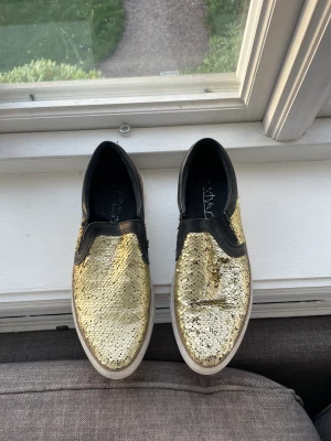 Guldiga sneakers - Säljer ett par jätte snygga guldiga skor som är för stora och därför aldrig använda! 