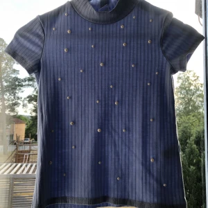 En blå tröja -  en blå tröja som går lite upp vid halsen och har små pärlor 🦋