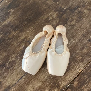 tåskor/balletskor  - Obrutna tåskor i storlek fem.  Provade i butik men annars aldrig använda. Ett par silikonsrumpor ingår.