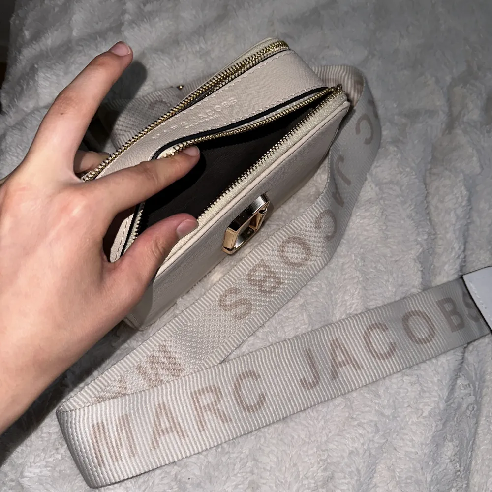 En helt ny och fräsch fake Marc Jacobs axelväska i beige/vit med guld detaljer. Den är oanvänd. Priset kan diskuteras!. Väskor.