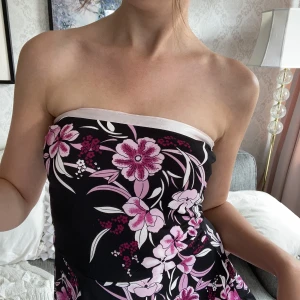 Axelbandslös klänning - En somrig klänning med rosa blomster, perfekt för ljumna sommarkvällar.