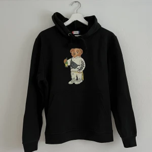 Hoddie - Svart hoddie med en björn på. Tröjan är använd och fortsatt fin men lite nopprig. 