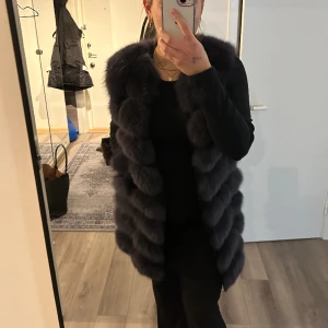 Äkta pälsväst - Säljer nu min fina pälsväst då den inte längre kommer till användning.  Det är äkta päls och den är köpt på Garoff. Orderbekräftelse finns som bevis på att det är äkta päls. Högra fickan är igensydd annars är den som ny. Köpt för 3000. Färgen är mörkgrå