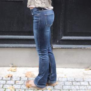 Beställningar görs via vår hemsida: thrifteddesign.one.   Ett par lågmidjade mörblåa bootcut jeans.