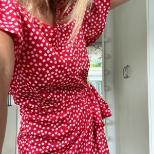 Sommarklänning! - Superfin röd sommarklänning med vita blommor på! Jättefin passform med knytning i midjan. Hör av er om ni har frågor ❤️