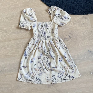 Gul klänning med blommor och puffärmar  - Använd en gång. Köpte för en avslutning men tyckte inte om hur den såg ut på mig så använde den aldrig mer. Köpt på H&M