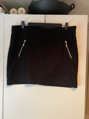 Kjol  - En svart kjol med fickor. Storlek: XL.