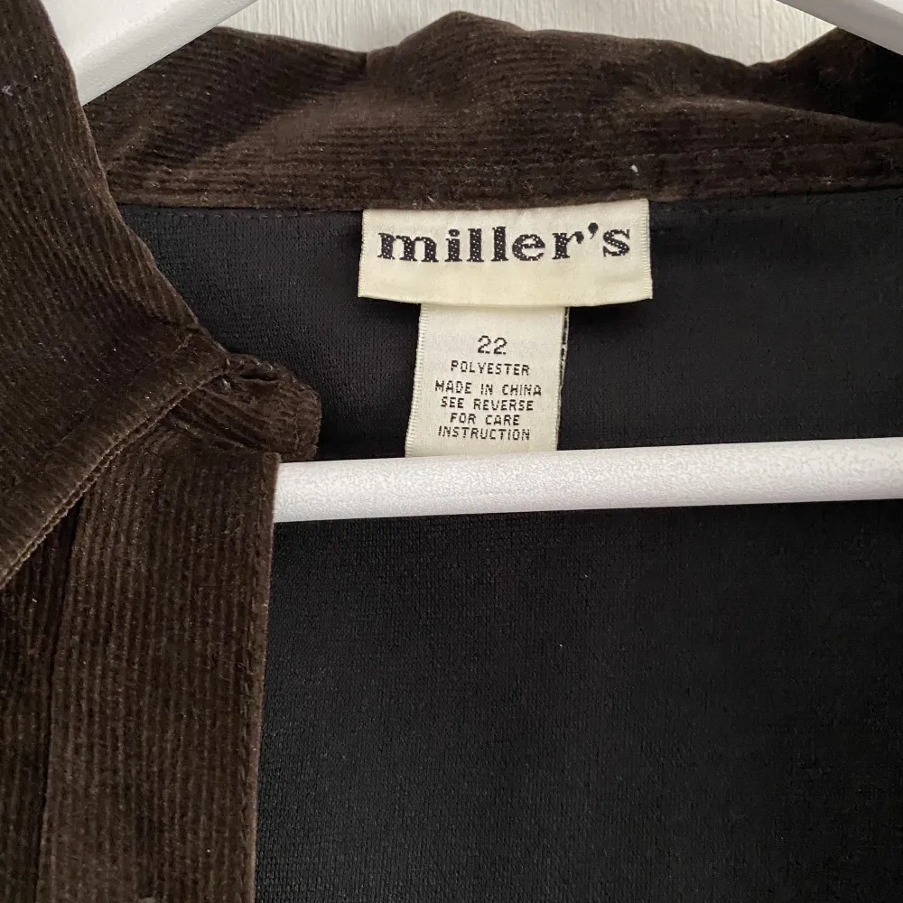 En mörkbrun skjorta i en slags blandning av manchester och sammet från Miller’s.  Skjortan har fjärils detaljer på båda sidorna av framsidan med strasstenar. Vissa av strassstenarna har dock ramlat av men man kan nog lätta sätta dit nya . Skjortor.
