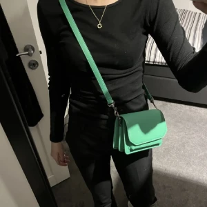 Handväska - Säljer denna gröna axelremsväska från NA-KD då den aldrig jag kommit till användning. Den är i nyskick utan defekter. Perfekt nu i sommar till olika festivaler och liknande, hör av er vid frågor eller andra funderingar 💚💚💚