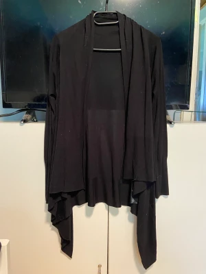 Lång kofta  - Svart lång kofta med volanger! Från HM storlek S! Fint skick aldrig använd! Perfekt till svala sommarkvällar täcker även benen!