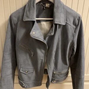 Ljusblå jacka  - Ljusblå kort jacka i mocka imitation, använd ca 2 ggr. Dragkedja & knappar. I strl 42 men den är liten i storleken. 