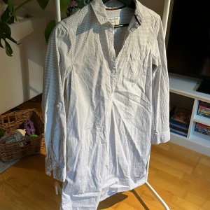 Snygg skjortklänning  - Snygg klassiskt randig skjortklänning i bomull i mycket fint skick, längd 87 cm, lätt utsvängd nedtill. Ärmar kan vikas upp och fästas med knapp. Sitter snyggt. 