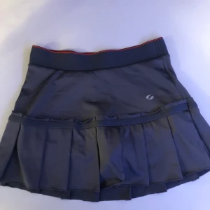 Tennis kjol - En supersöt tennis kjol i grått med rosa orangea shorts under. Inte använd så mycket så den är i fint skick. Stl.XS/S