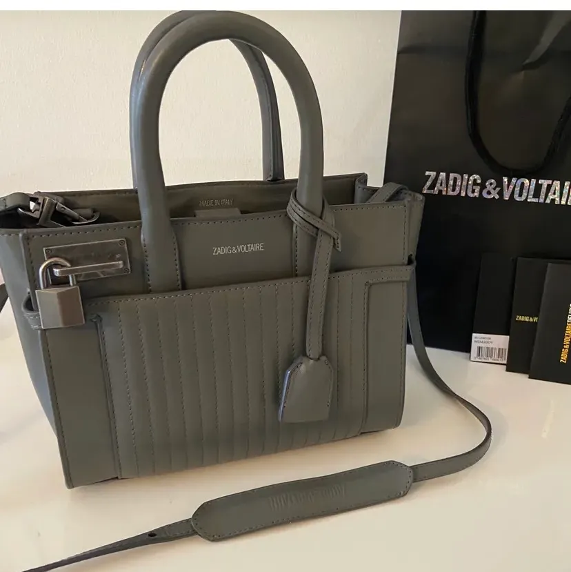 Säljer denna fina gråa väska från Zadig & Voltaire i modellen Candide XS. Säljs inte längre och väskan är i mycket fint skick. Väskan är rymlig och har justerbart och avtagbart crossbody band. Prislapp finns kvar, nypris ca 4500 kr, hör av er vid frågor!. Väskor.
