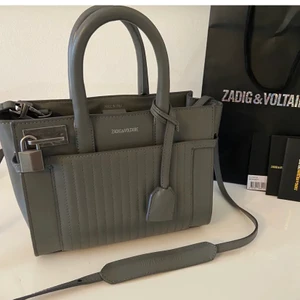 Zadig Voltaire väska - Säljer denna fina gråa väska från Zadig & Voltaire i modellen Candide XS. Säljs inte längre och väskan är i mycket fint skick. Väskan är rymlig och har justerbart och avtagbart crossbody band. Prislapp finns kvar, nypris ca 4500 kr, hör av er vid frågor!