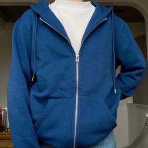 Zip-up hoodie i en fin blå färg som sitter snyggt oversize på mig som är en storlek S. Köparen står för (spårbar) frakt!