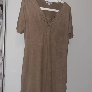 Aktive usa T-shirt lr kort klänning st L - Mycket snygg sand färgad T-shirt med knähöga stövlar till. Man kan ha den som T-shirt lr klänning. Mocka material.  Lite ocersize. Det finns en fläck dessvärre som ej försvunnit i tvätten, se bild! 