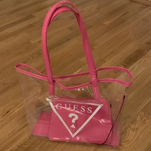 Äkta Guess väska - Äkta guess väska i genomskinligt och rosa material. Original pris 700kr. En liten necessär kommer med väskan. Perfekt för din y2k Paris Hilton look. Guess säljer inte längre denna väska