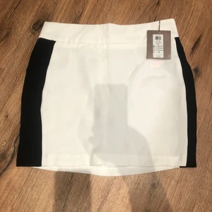 Vit kjol med svarta sidor - MIKO SKIRT storlek S. Helt oanvänd. Finns en lite fläck som kommit vid transport som knappt syns. Kolla andra tredje bild. Original pris 300kr