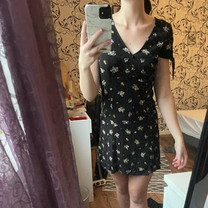 Klänning  - Svart klännning med gula blommor från hm i storlek 36. Knytdetaljer på axlarna och insydda knappar vid bröstet. Knappt använd. Endast swish och frakt tillkommer 