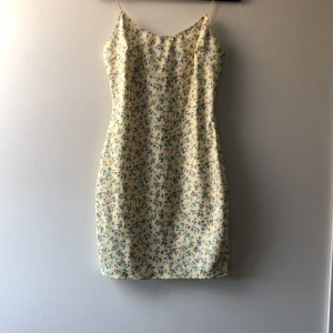Blommig klänning från Nelly  - Superfin sommarklänning i storlek M. Alldrig använd då det är förstod för mig och hann inte lämna tillbaka. Nyskick. Sitter tajt, har tunna band och slutar på mitten av låren ungefär. Gul med lila/blå blommor på. Från Nelly one. Jag står för frakten 