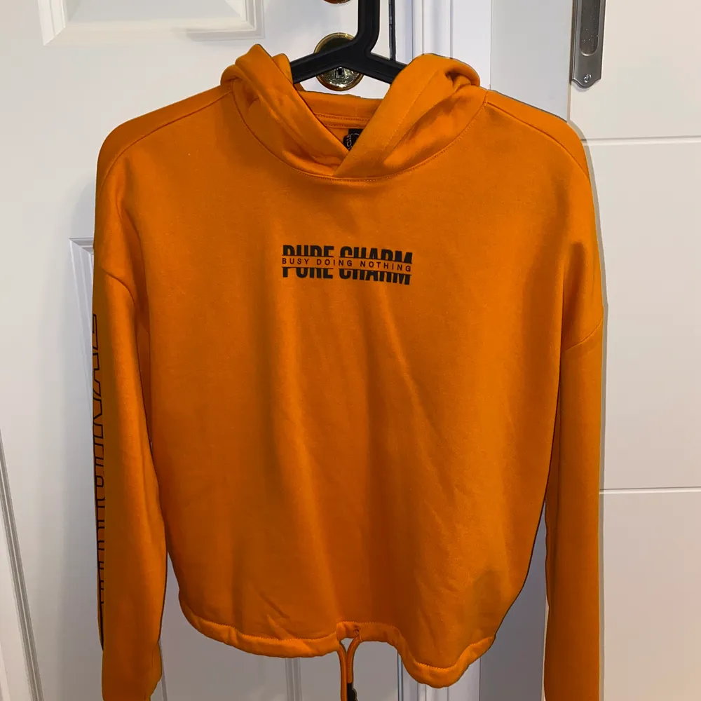 En fin orange hoodie som aldrig har kommit till användning i storlek XS. Det går att dra åt vid nedre delen av hoodien.. Hoodies.