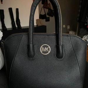 Väska - Säljer denna super snygga väska i svart ( inte äkta MK ) men fortfarande super fin och perfekt storlek enligt mig själv. Den har även två små fack och ett lite större fack med dragkedja där i. Sen kan man även stänga väskan med dragkedja. Allt är i guldetalj och de medkommer även ett lite längre band som gör så att man inte bara behöva bära den som en handväska. 