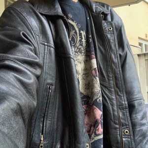 Svart lång skinnjacka - Gammal svart skinnjacka från okänt märke. Jackan är väldigt lång så det var svårt att få med hela på bild. Fråga gärna om fler bilder vid intresse! Jackan är i bra skick om man bortser från att jackans hank har gått av. Vet inte vilken storlek det är på jackan men ja i åtanke att jag är 190 cm lång