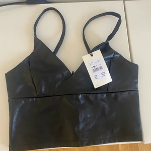 Helt ny crop top - Svart crop top i PU material/skinnimitation. Från BikBok. Aldrig använd, lappen kvar. Dragkedja i ryggen. Ord pris 249 kr