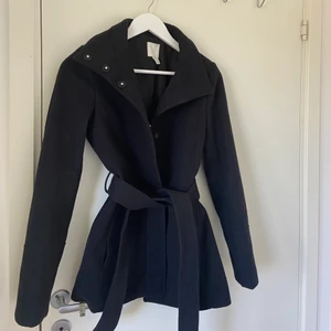 Mörkblå kappa från H&M - Mörkblå kapp från H&M storlek 34. Perfekt höstjacka, varm och skön. Knappar som stänger jackan. Perfekt längd. Köpt för ca 2 år sen! En knapp gick av men sydde lätt ihop den! Det finns ett hål i insidan av armen, men som är lagat. Skriv för fler bilder. ☺️☺️ 