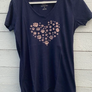 Blå T-shirt med tass märke - Trevlig T-shirt med tassar som formar ett hjärta