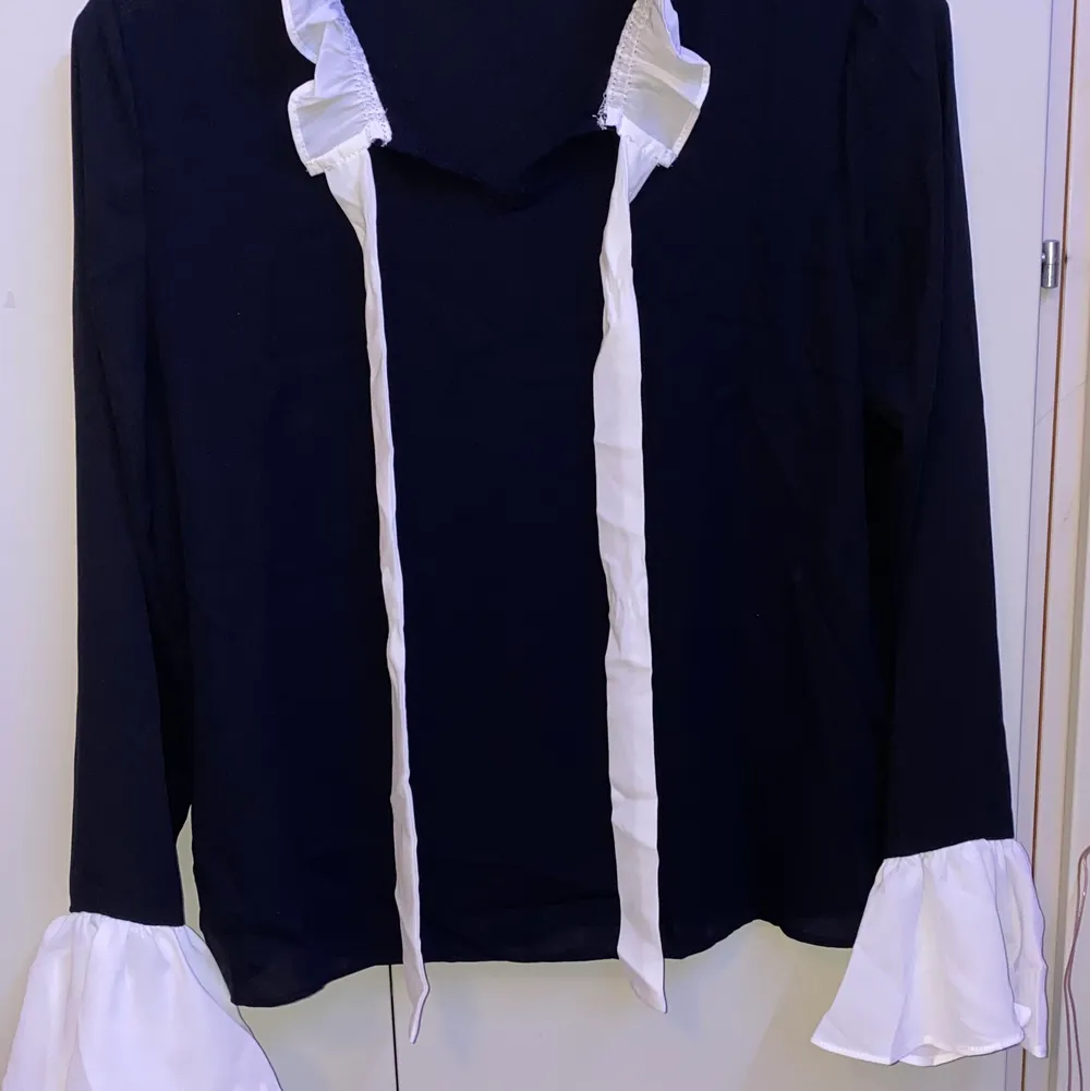 Black bell sleeve blouse, with a self tie neck.. Blusar.